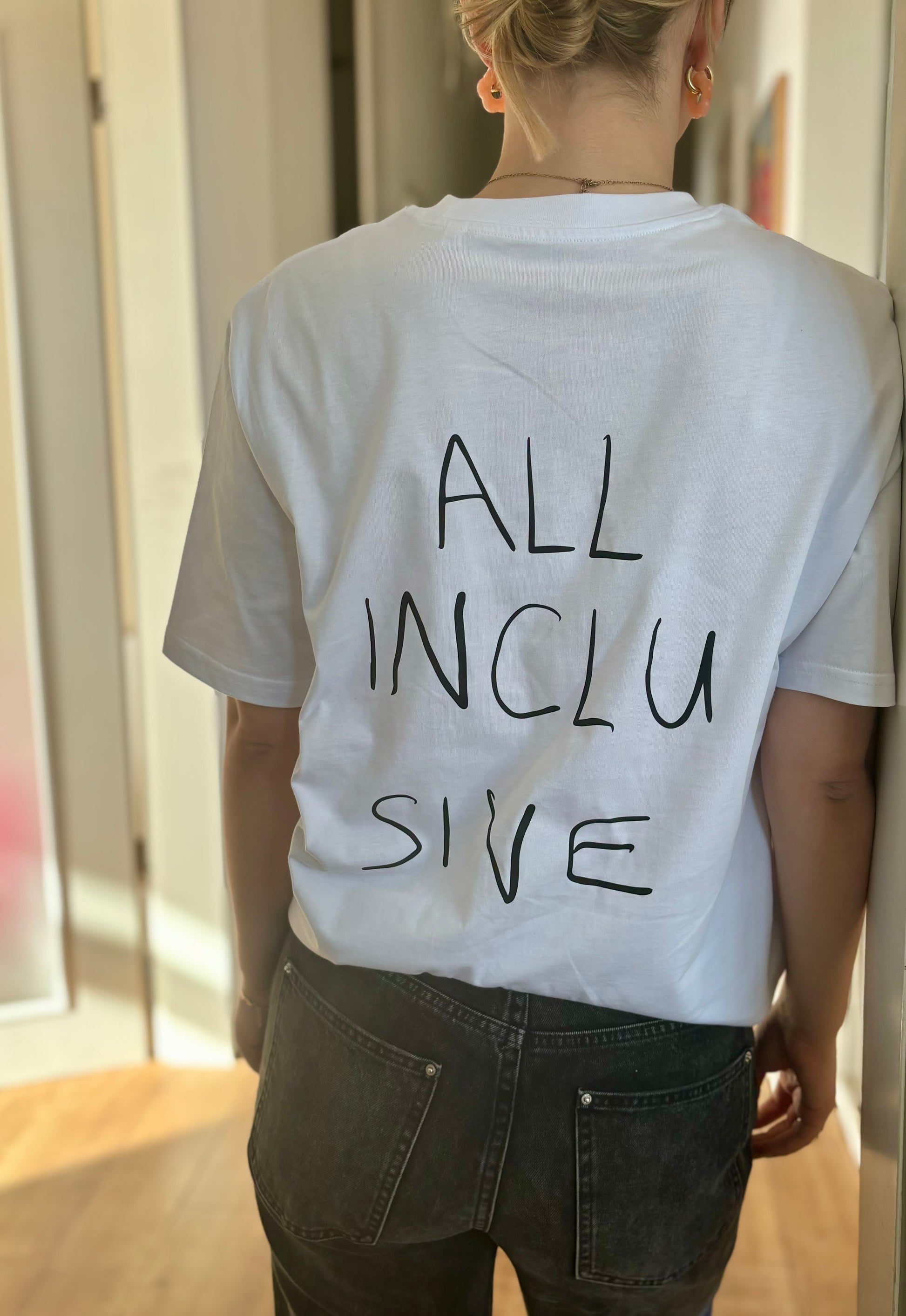 Foto vom T-Shirt "All Inclusive" von hinten. Auf dem Shirt ist ein großer Schriftzug handgeschrieben mit "All Inclusive"
